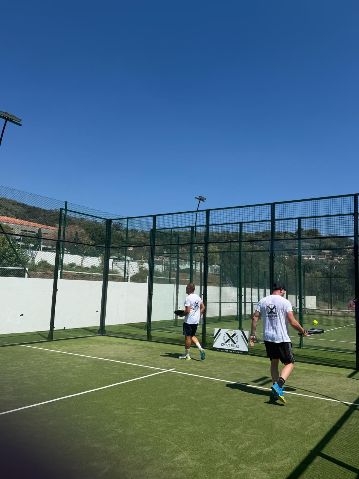 Deux joueurs Cross Padel lors d'un échange devant le panneau du club